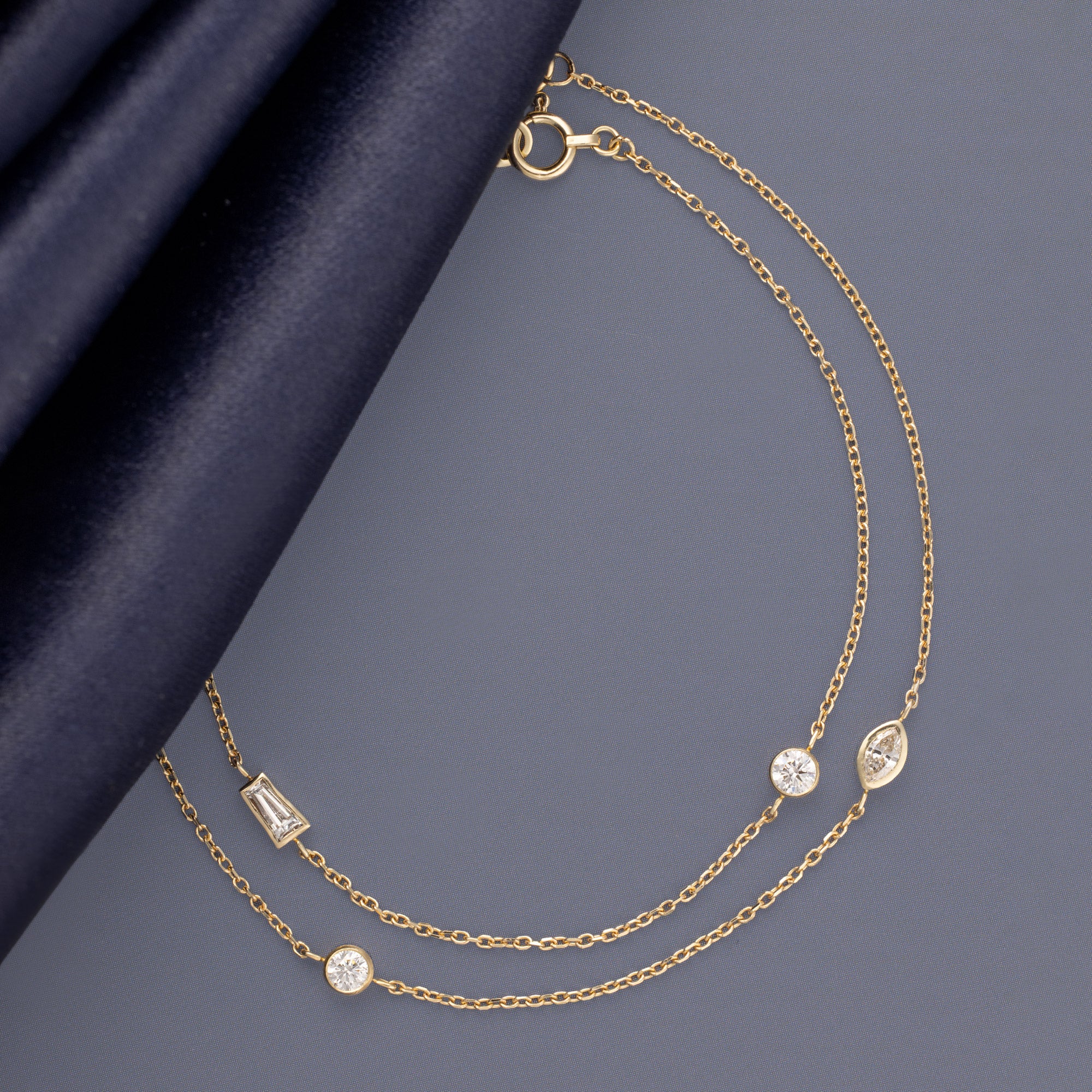 Marquis Diamond and Baguette Diamond Chain Bracelets in 10K Yellow Gold on Muted Blue Background