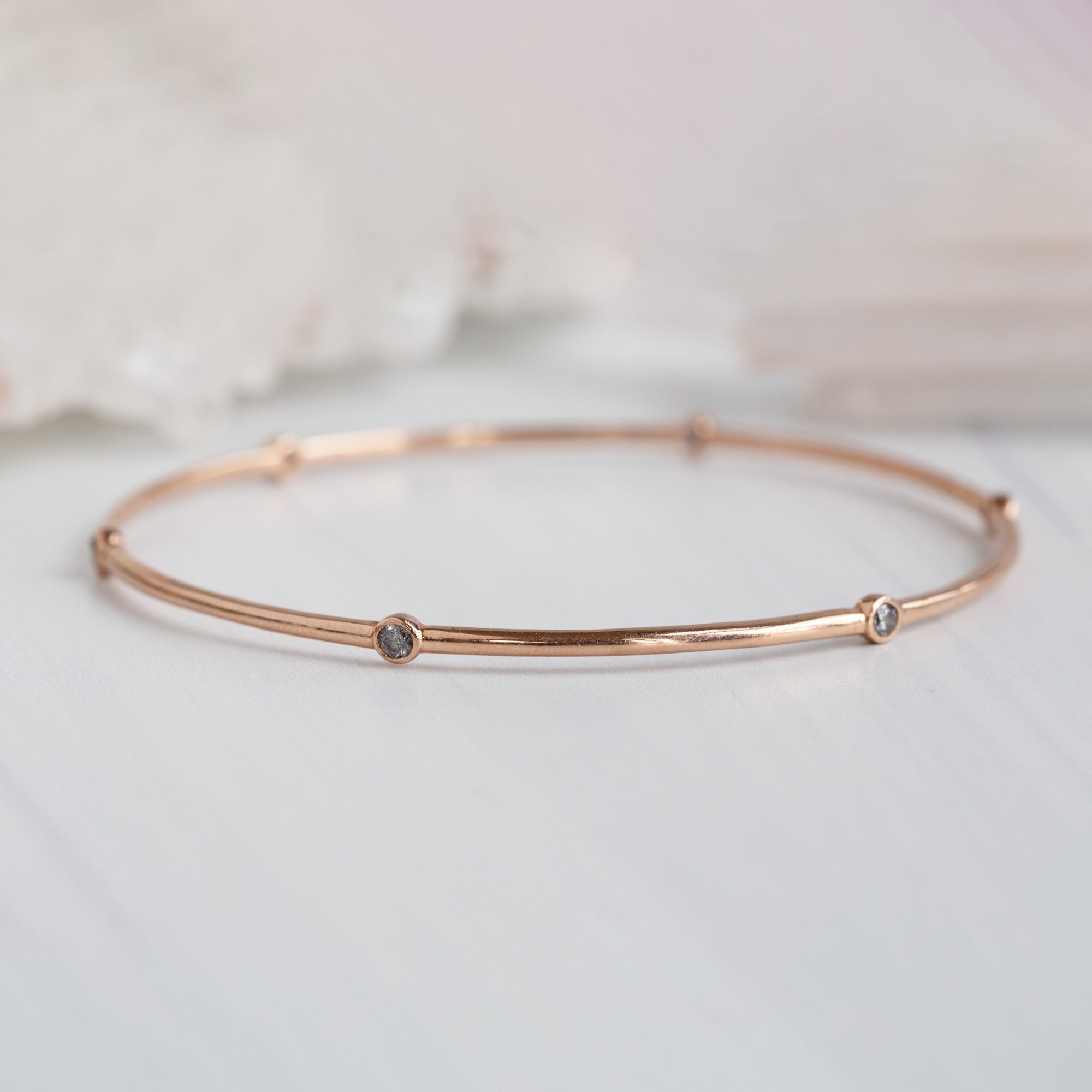 The Salt and Pepper Diamond Constellation Bangle in 14K Rose Gold on White Marble