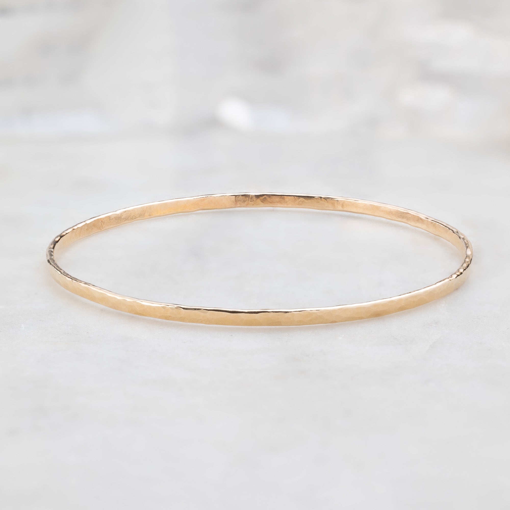 The Hammered Stacking Bangle in Yellow Gold Filled on White Marble