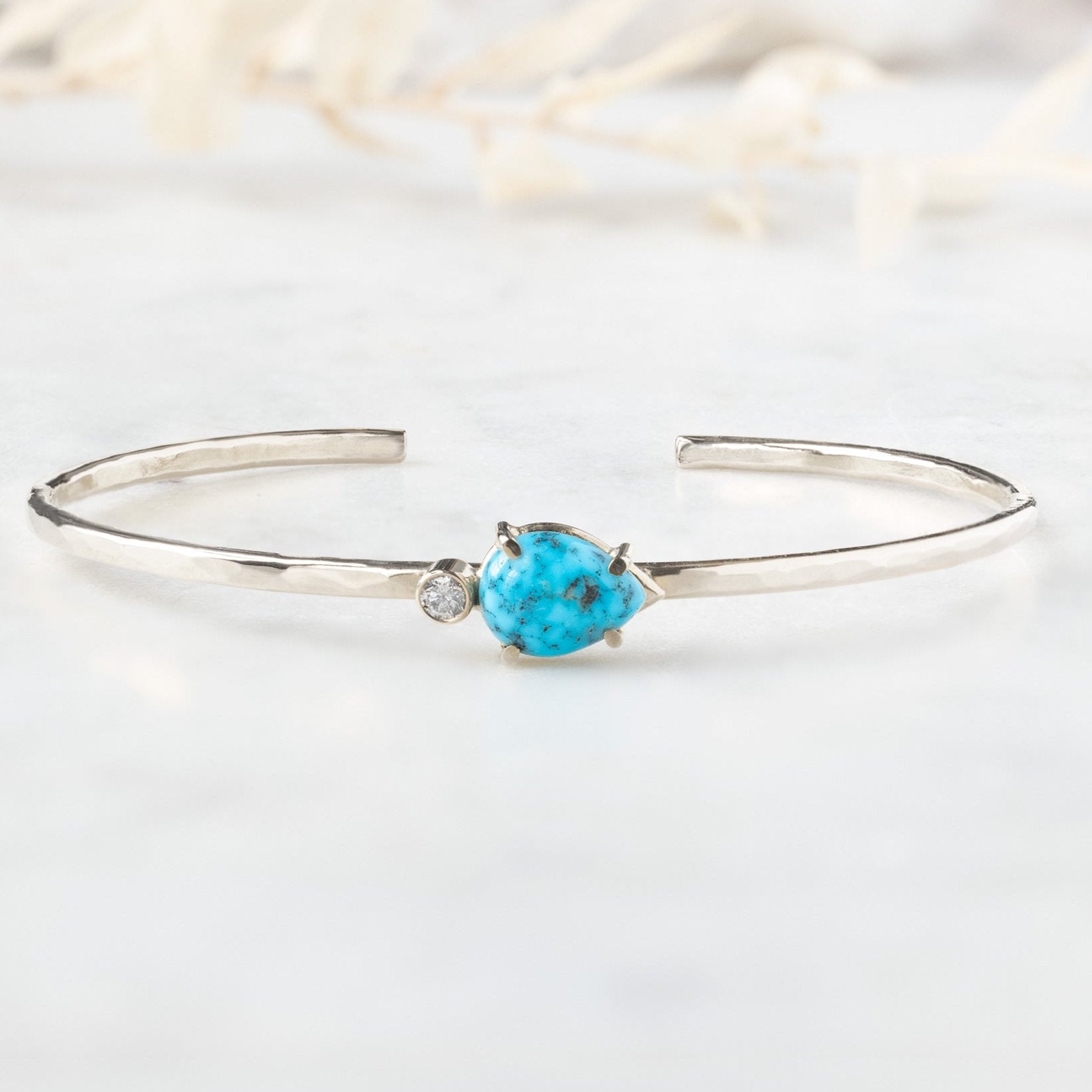 The Asymmetrical Turquoise + Diamond Cuff Bracelet in Sterling Silver on White Marble