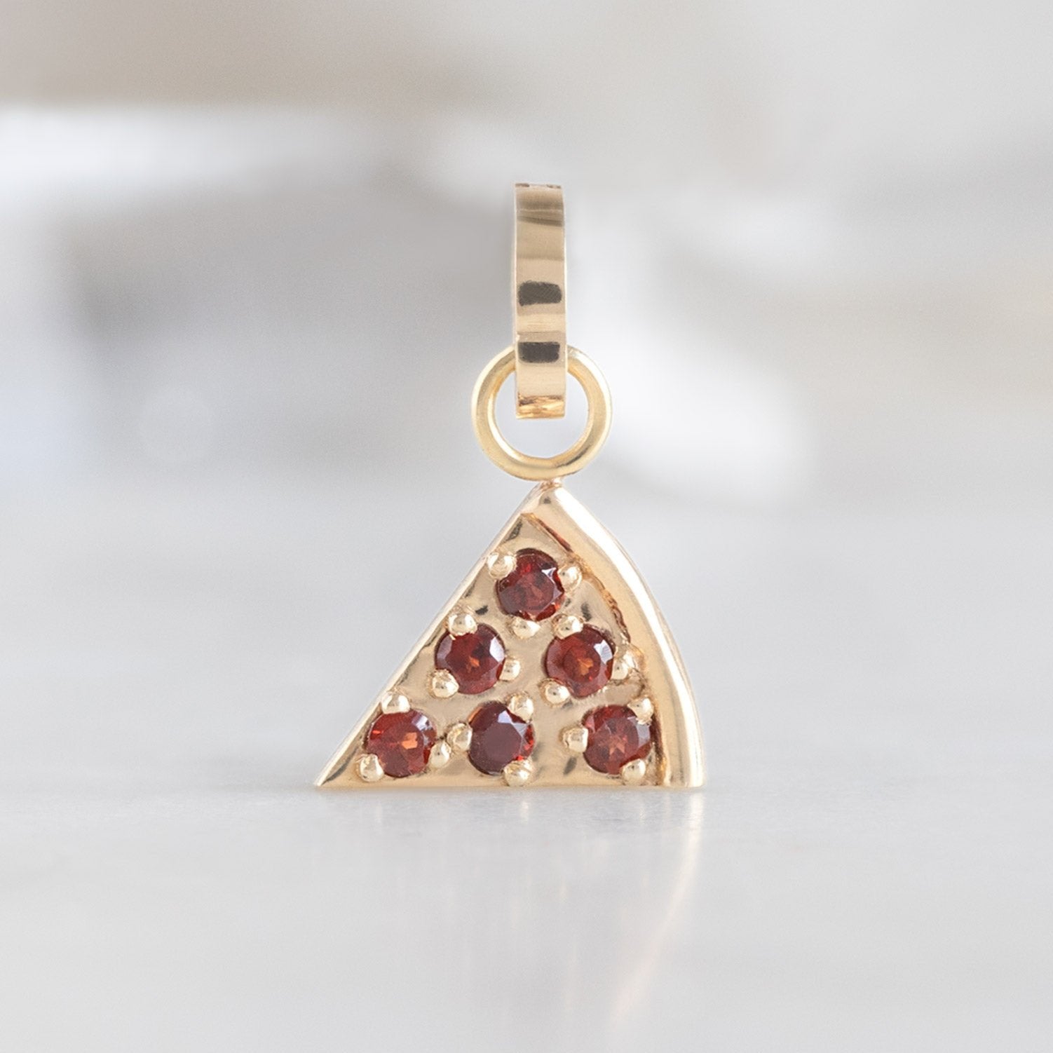 The Pizza Slice Charm in 10K Yellow Gold on White Marble