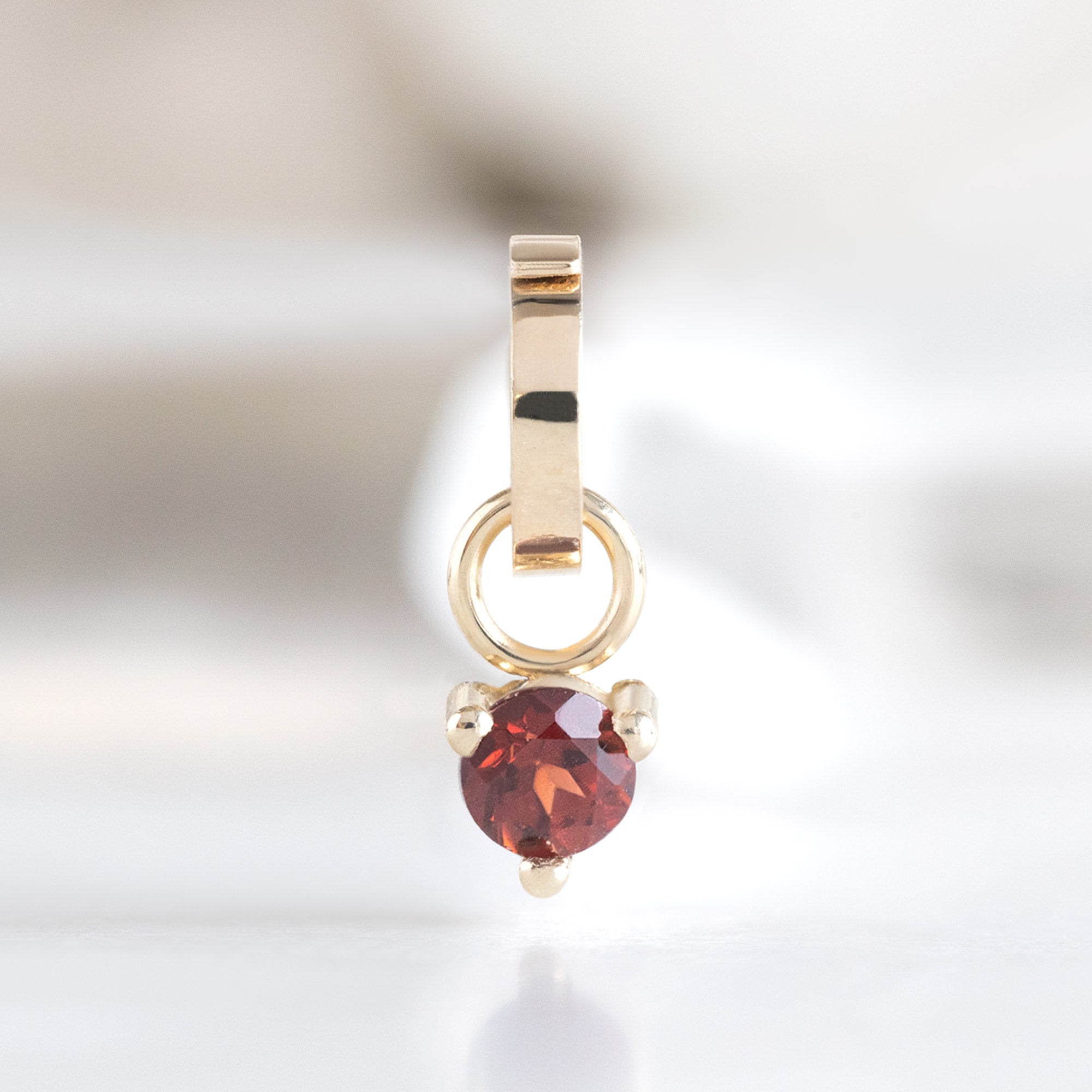 The Garnet Birthstone Charm in 10K Yellow Gold on White Marble