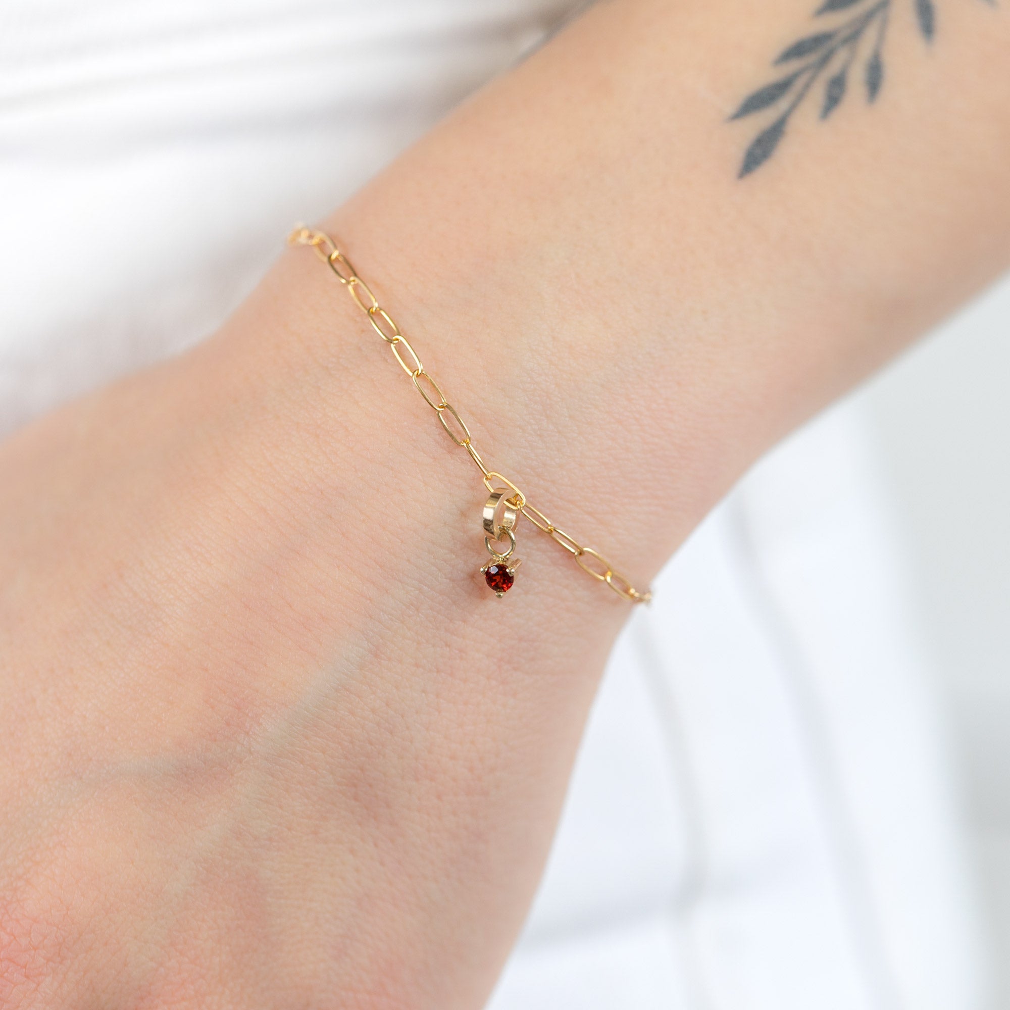 The Garnet Birthstone Charm in 10K Yellow Gold on Drawn Cable Chain Bracelet on Model