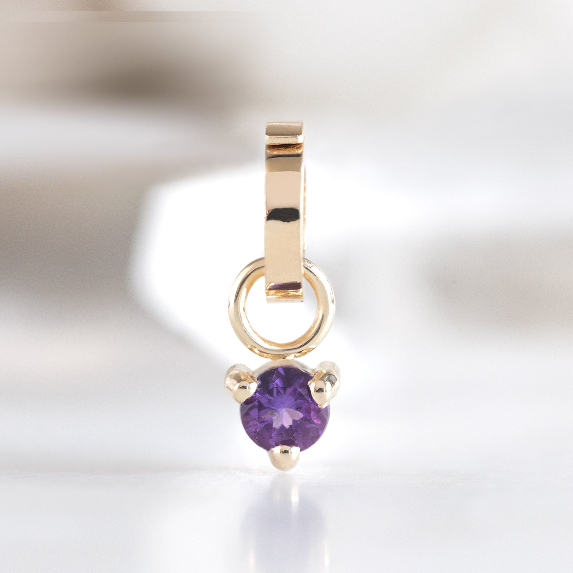 The Amethyst Birthstone Charm in 10K Yellow Gold on White Marble