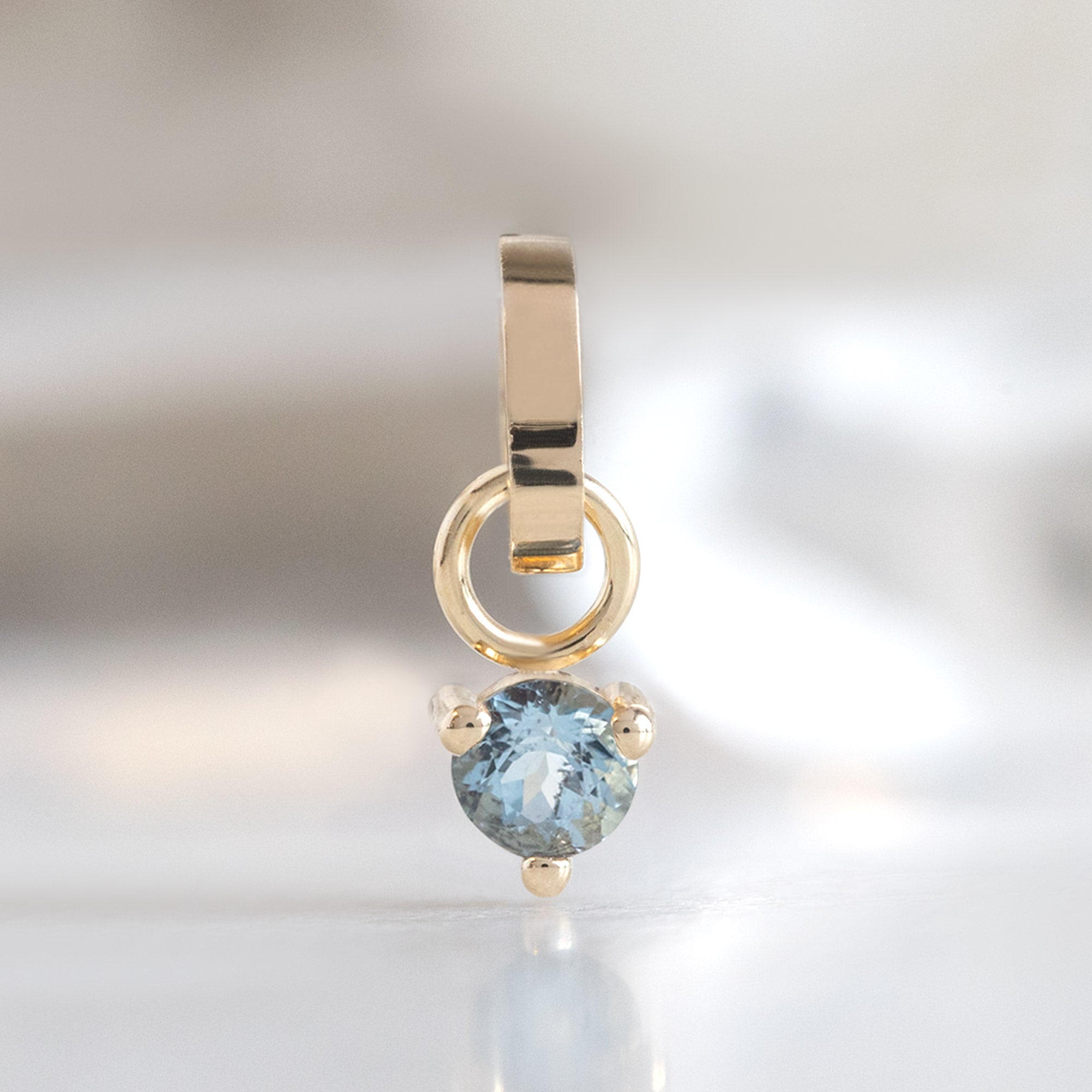 The Aquamarine Birthstone Charm in 10K Yellow Gold on White Marble