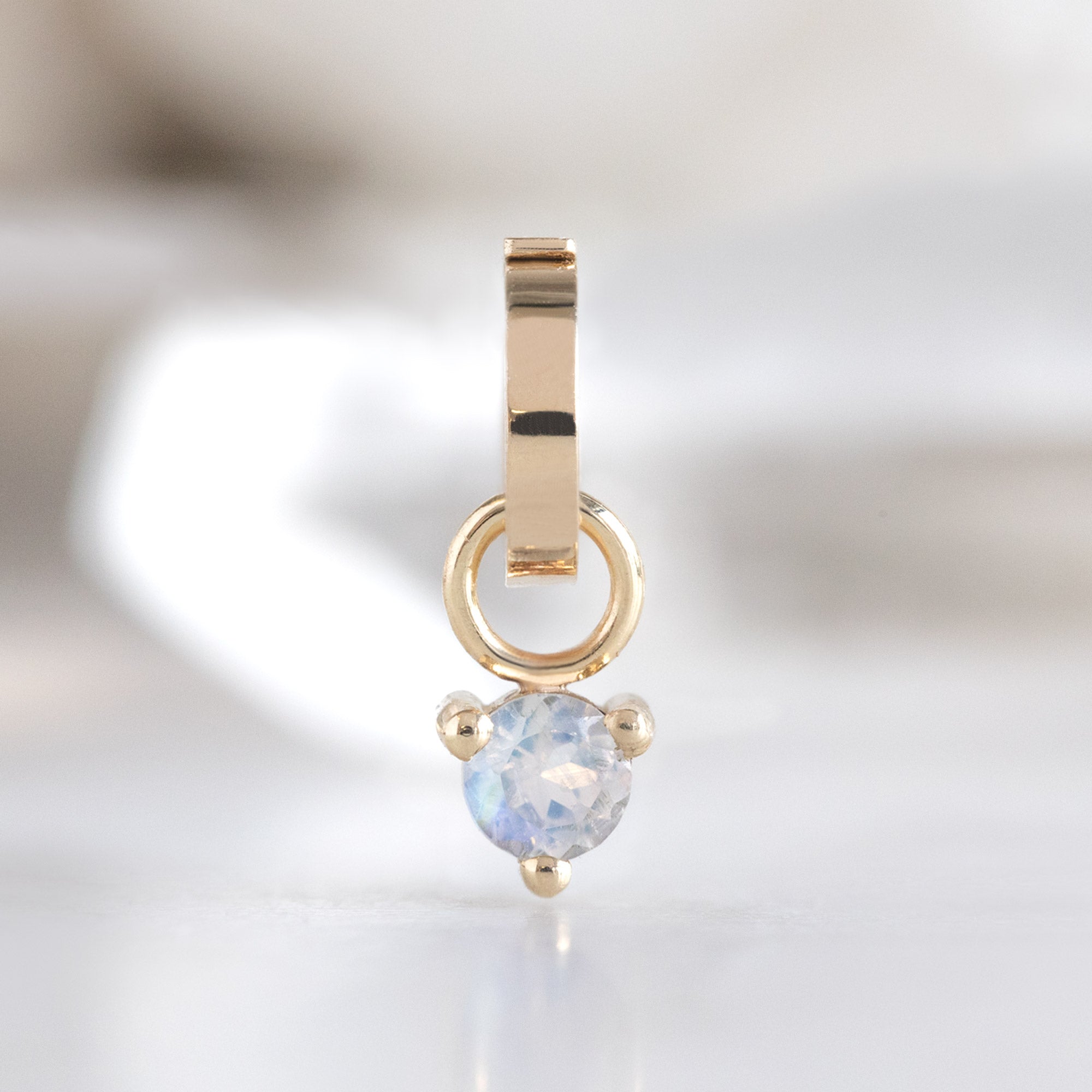 The Moonstone Birthstone Charm in 10K Yellow Gold on White Marble