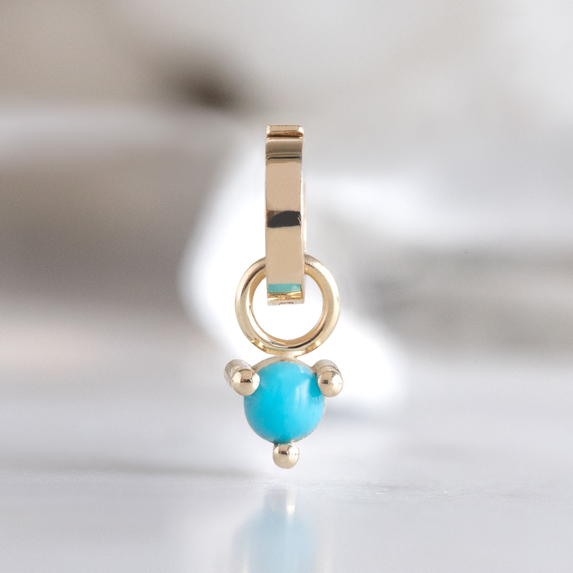 The Turquoise Birthstone Charm in 10K Yellow Gold on White Marble