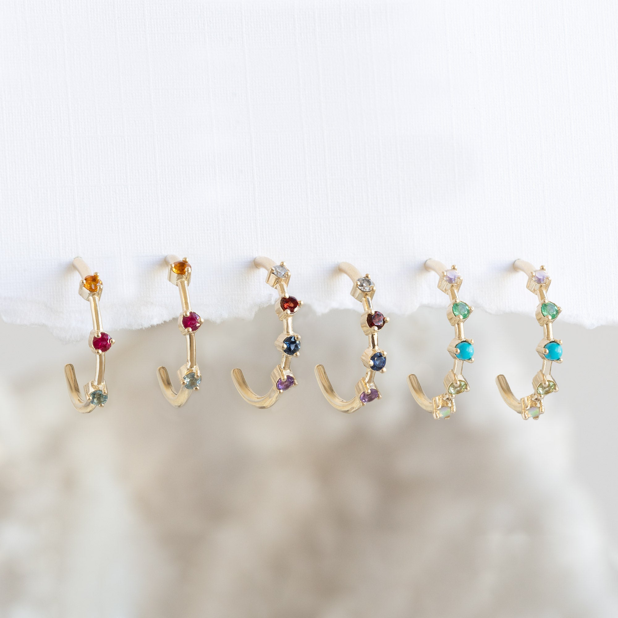 Custom The Multi-Birthstone Hoops
with all stone options hanging on white textured paper