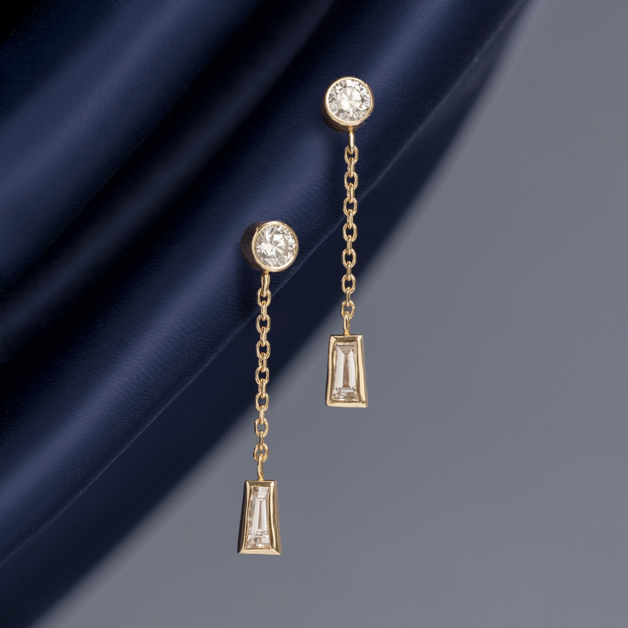 ‘Date Night’ Baguette Diamond Drop Earrings in 10K Yellow Gold hanging on navy blue fabric