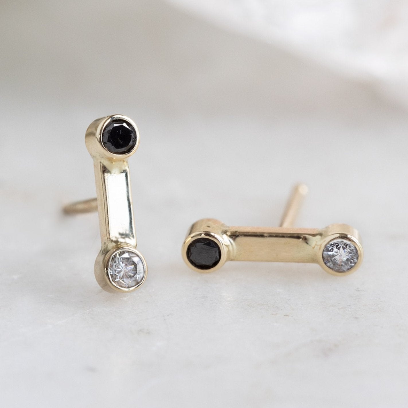 The Duality Diamond Stud Earrings in 14K Yellow Gold on White Marble