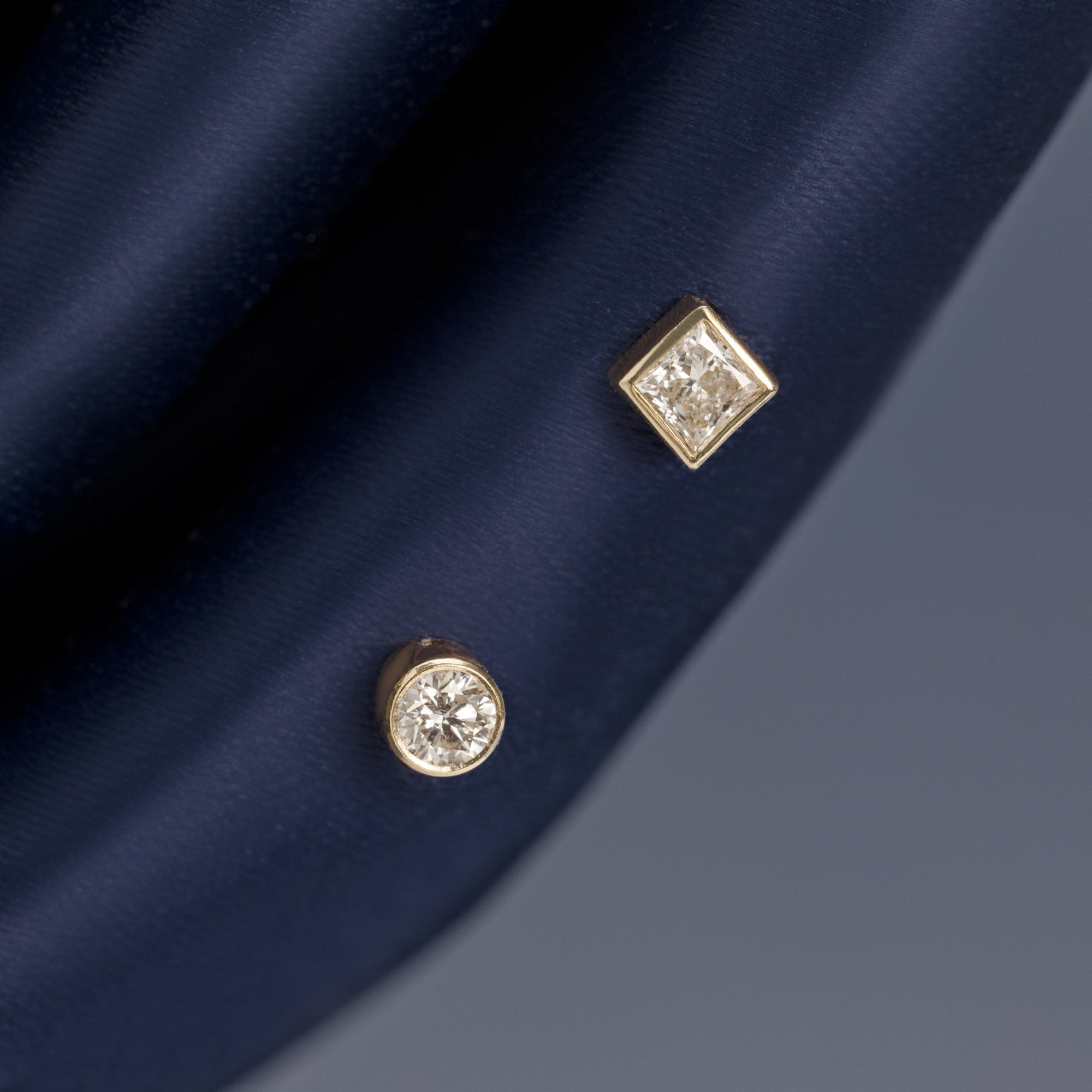 'It Girl' Round + Geometric Diamond Stud Earrings in 14K Yellow Gold hanging on navy blue fabric