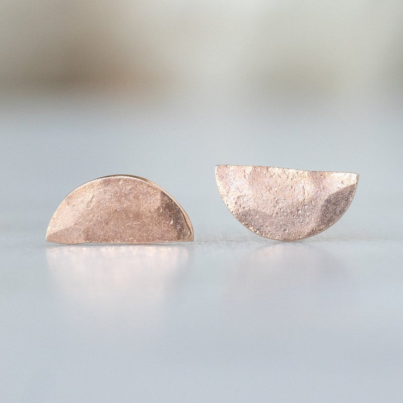 The Gold Half Moon Stud Earrings in 14K Rose Gold on White Marble