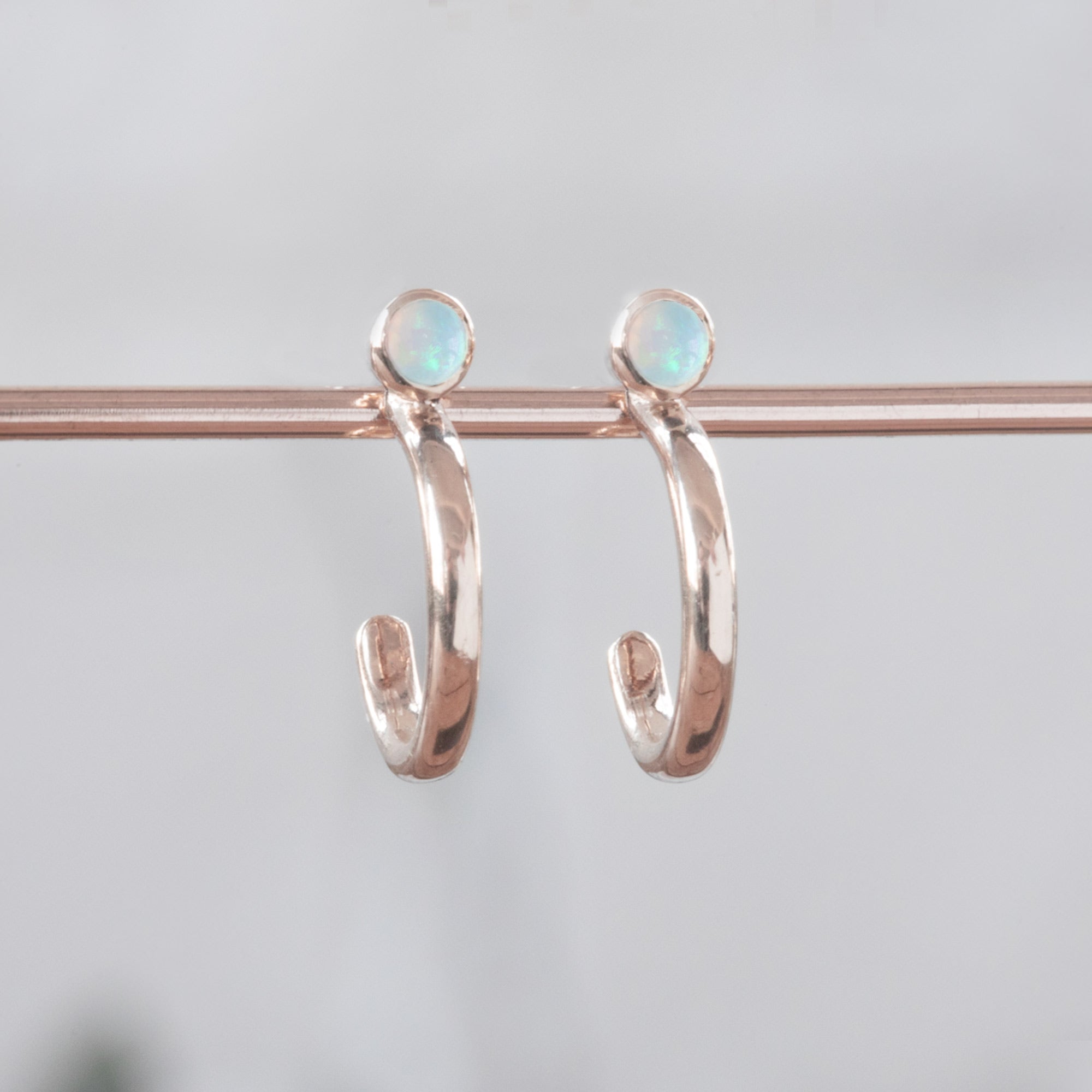 Custom Opal Birthstone Hoop Earrings | 14K Rose Gold displayed on holding bar.