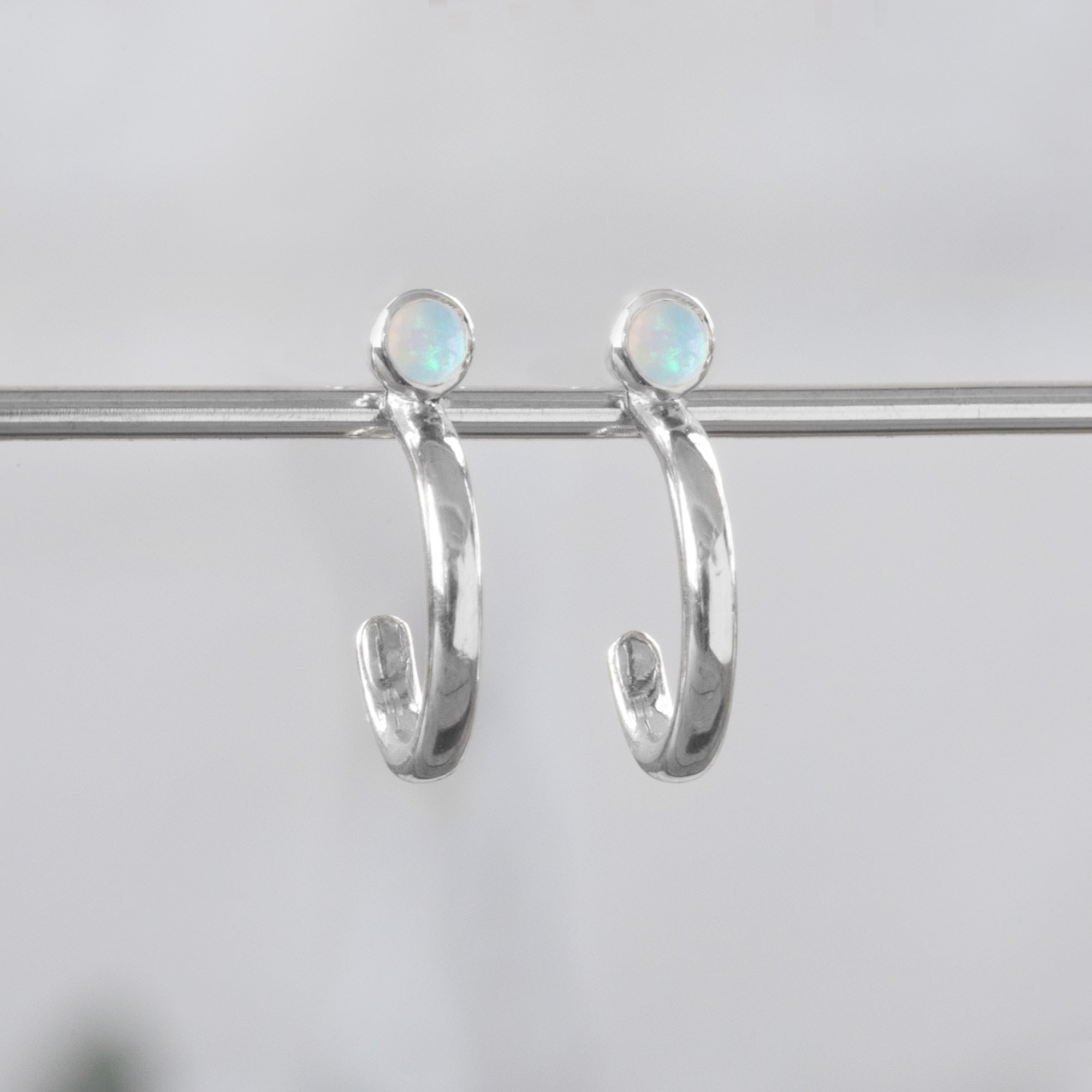 Custom Opal Birthstone Hoop Earrings | 14K White Gold displayed on holding bar. 