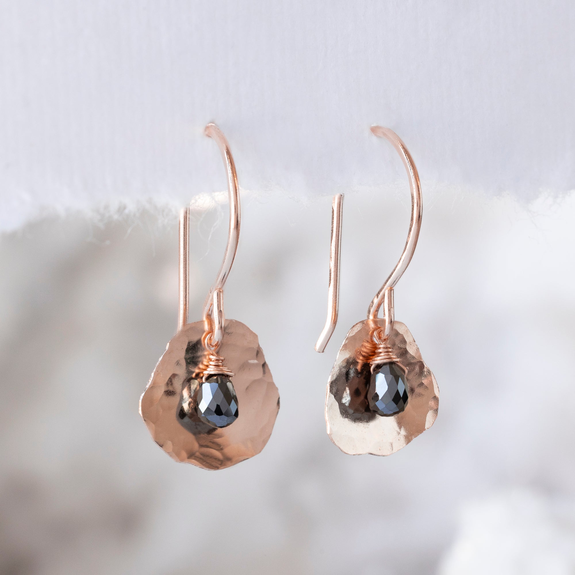 The Black Diamond Petal Earrings in Rose Gold Filled hanging on white paper