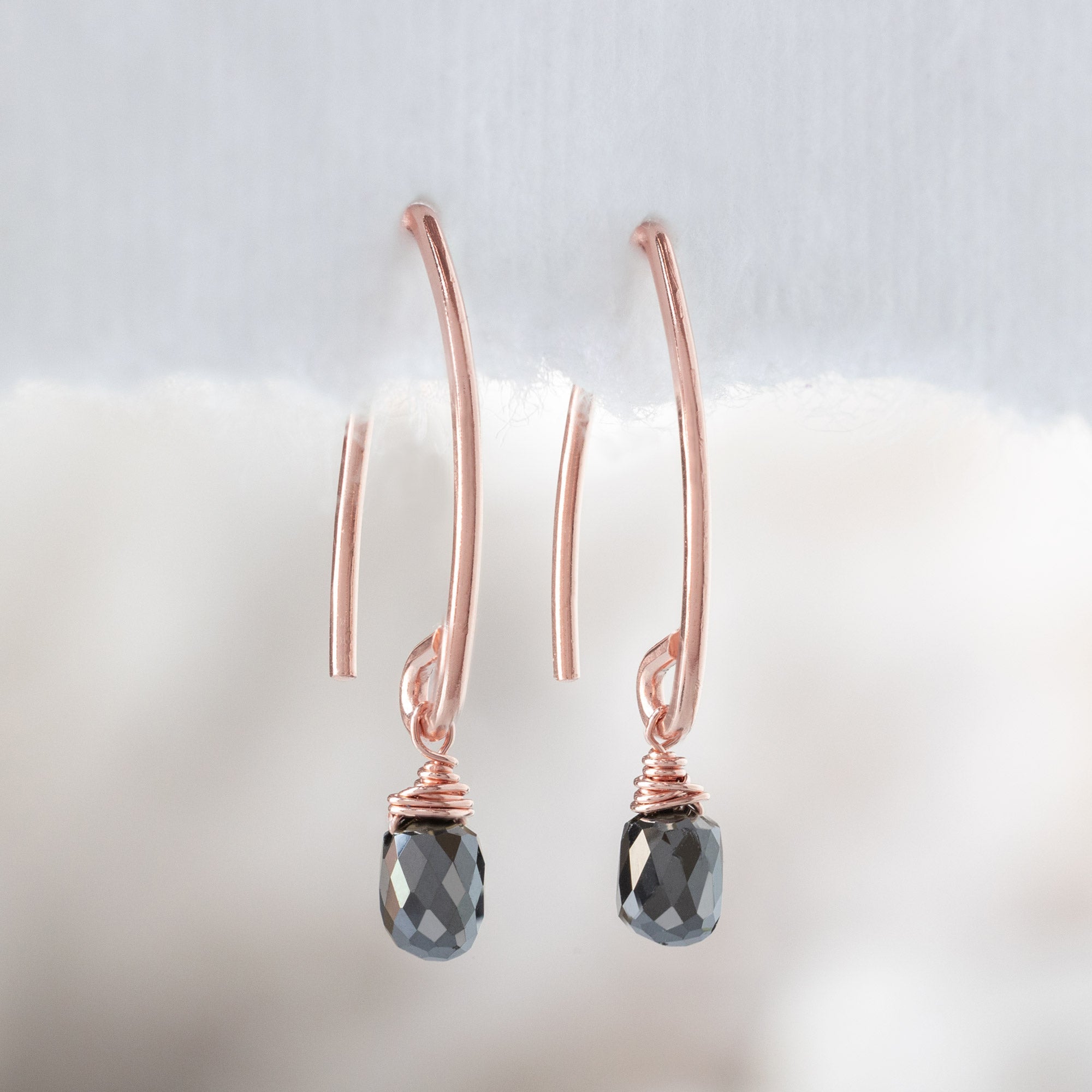 The Simple Black Diamond Drop Earrings in Rose Gold Filled hanging on white textured paper