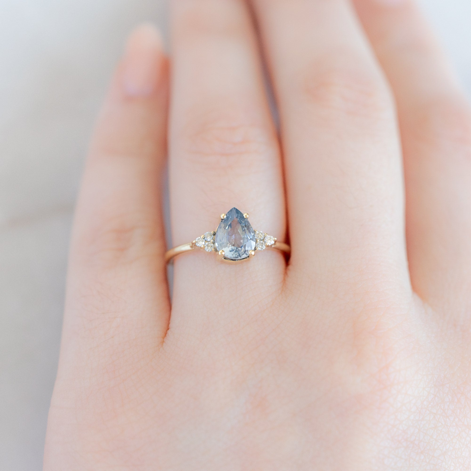 The Ivy Ring | 1.5ct Pear Cut Sapphire in 14K Yellow Gold displayed on model's left hand ring finger. 