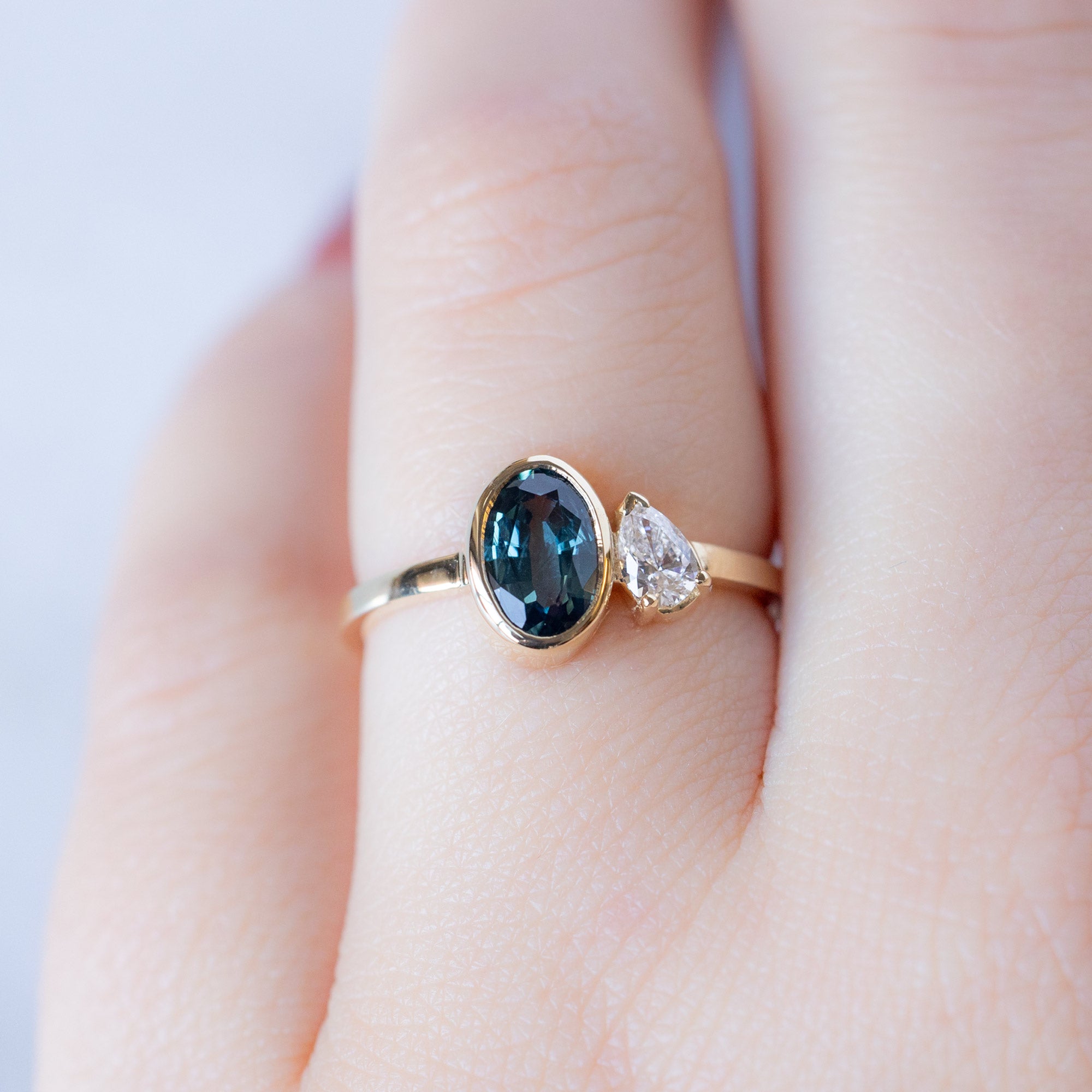 The You and Me Ring with a 1.11ct Oval Cut Sapphire in 14K Yellow Gold on Marble