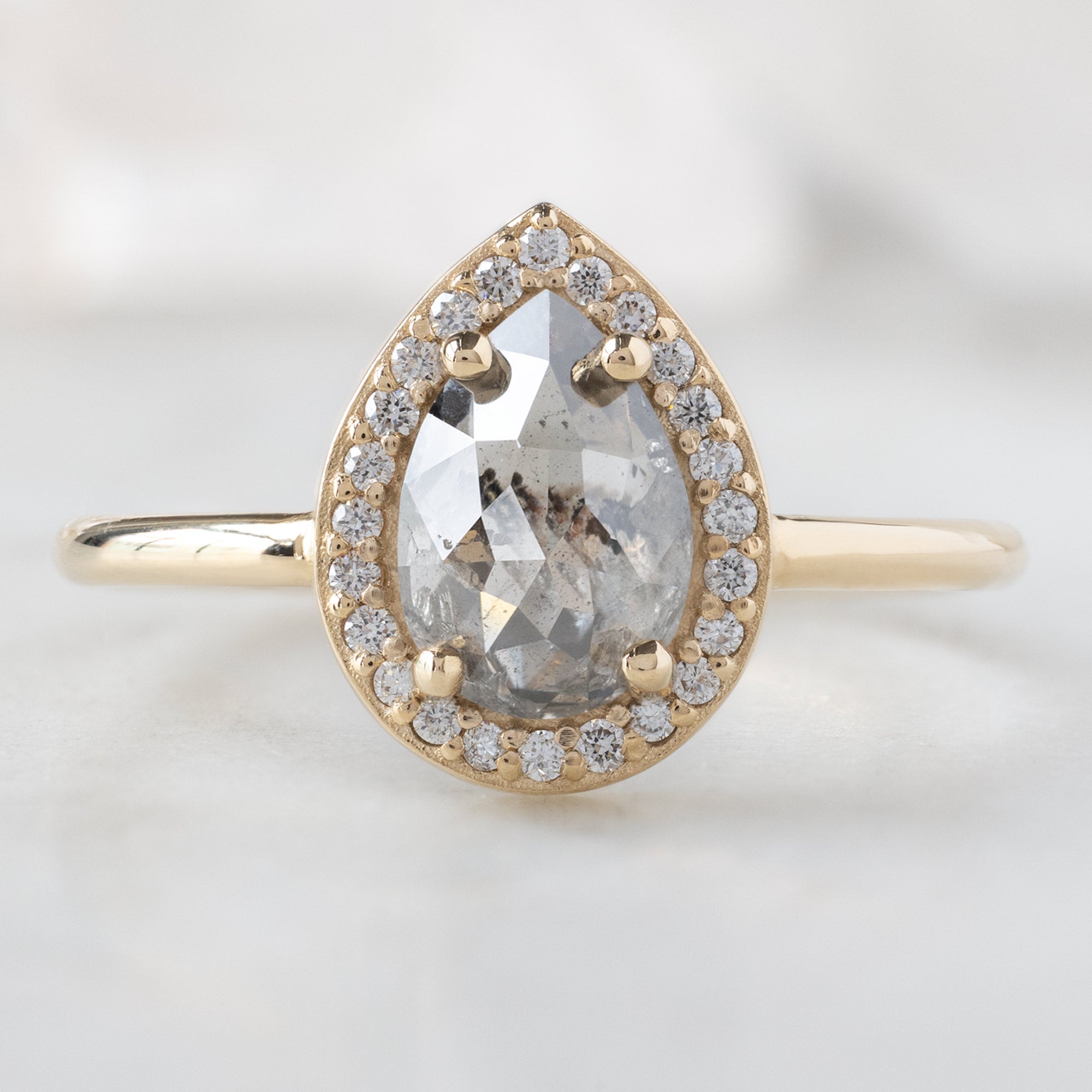 The Dahlia Ring with a 1.12ct Pear Salt and Pepper Diamond in 14K Yellow Gold on White Marble