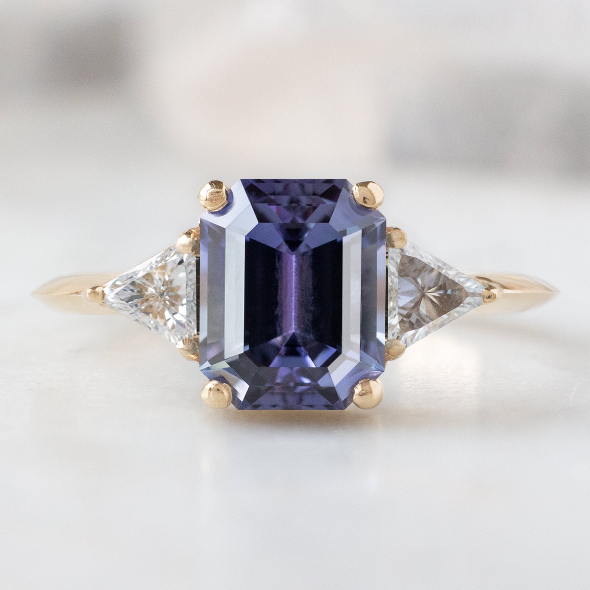 The Jade Ring with a 1.91ct Emerald Cut Purple Tanzanite in 14K Yellow Gold on White Marble