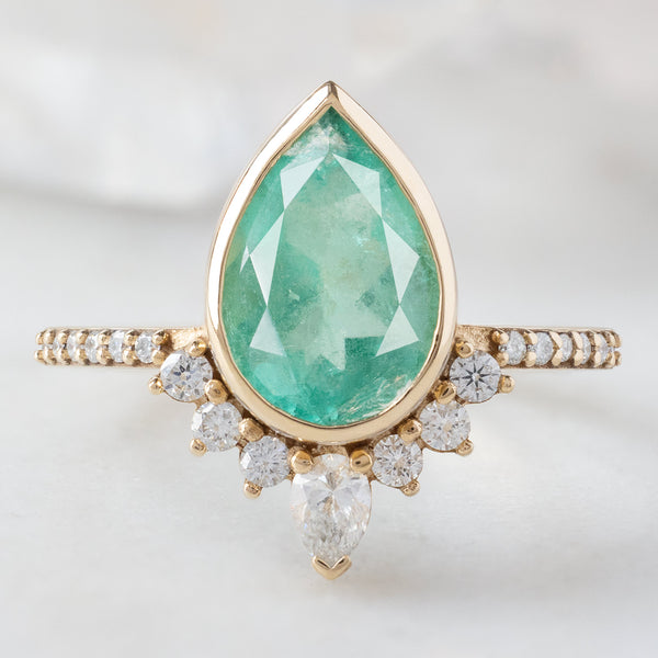 The Aster Ring with a 2.12ct Pear Emerald in 14K Yellow Gold on White Marble