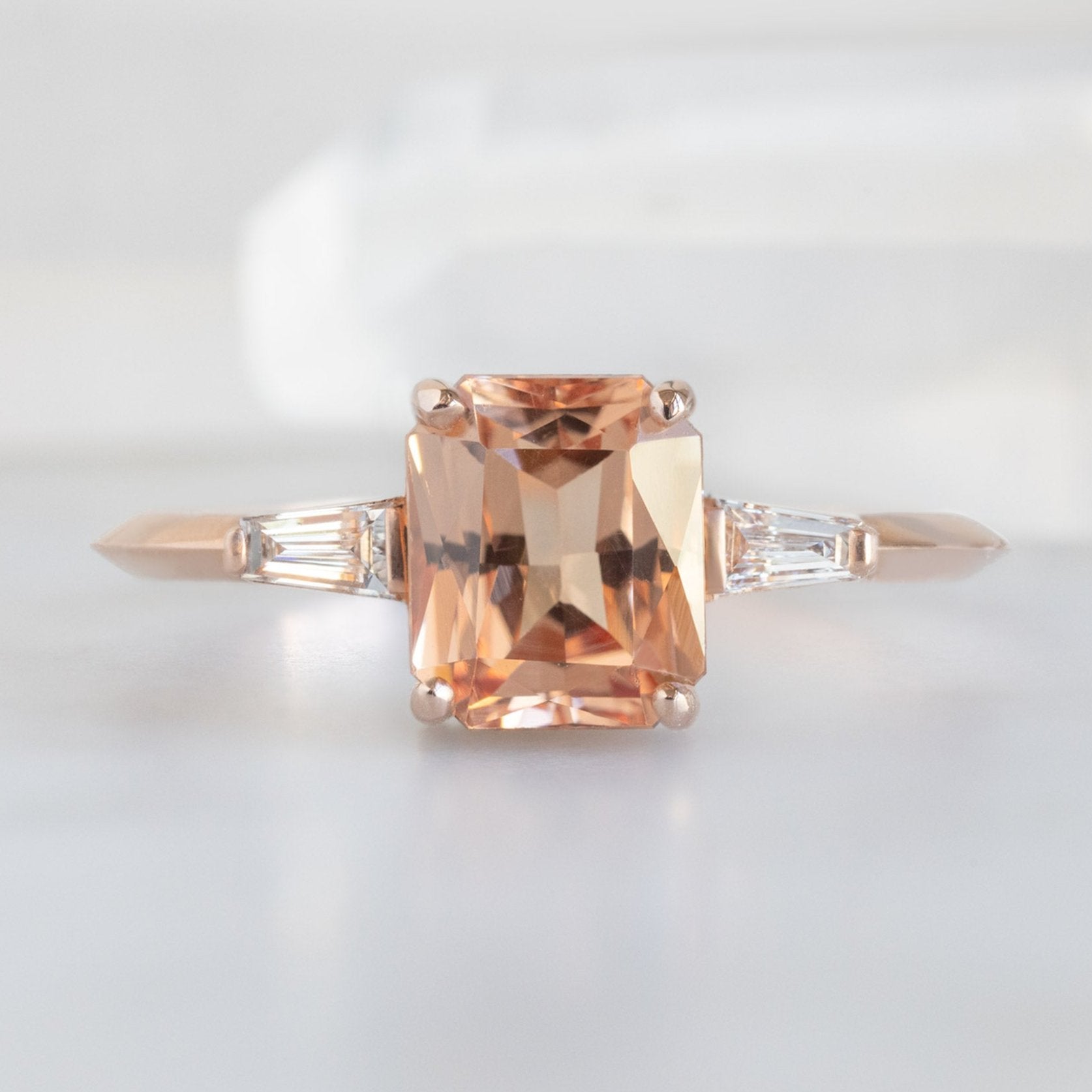 The Ash Ring | 1.43ct Emerald Cut Garnet in 14K Rose Gold displayed on marble surface. 