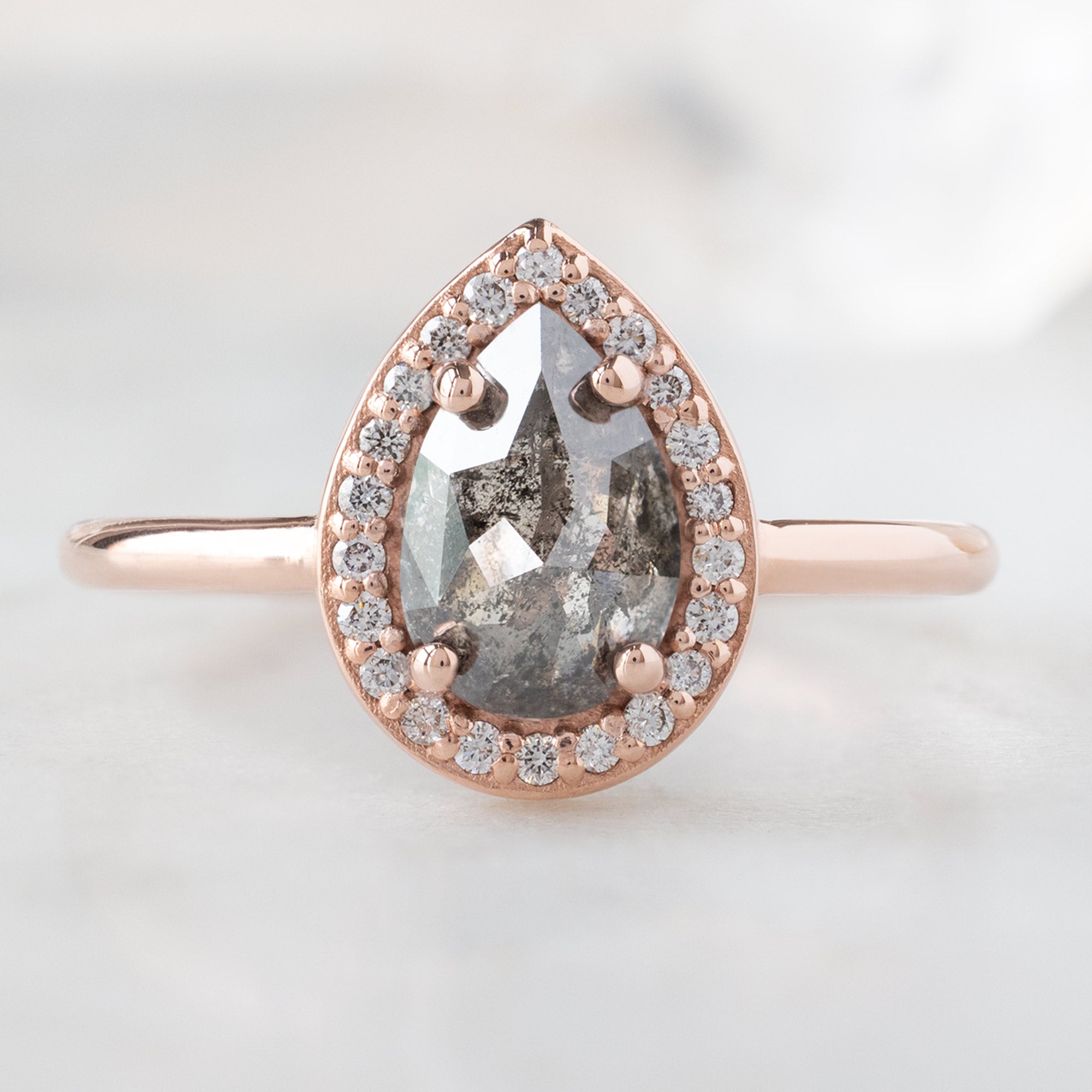 The Dahlia Ring with a 1.09ct Pear Salt and Pepper Diamond in 14K Rose Gold on White Marble