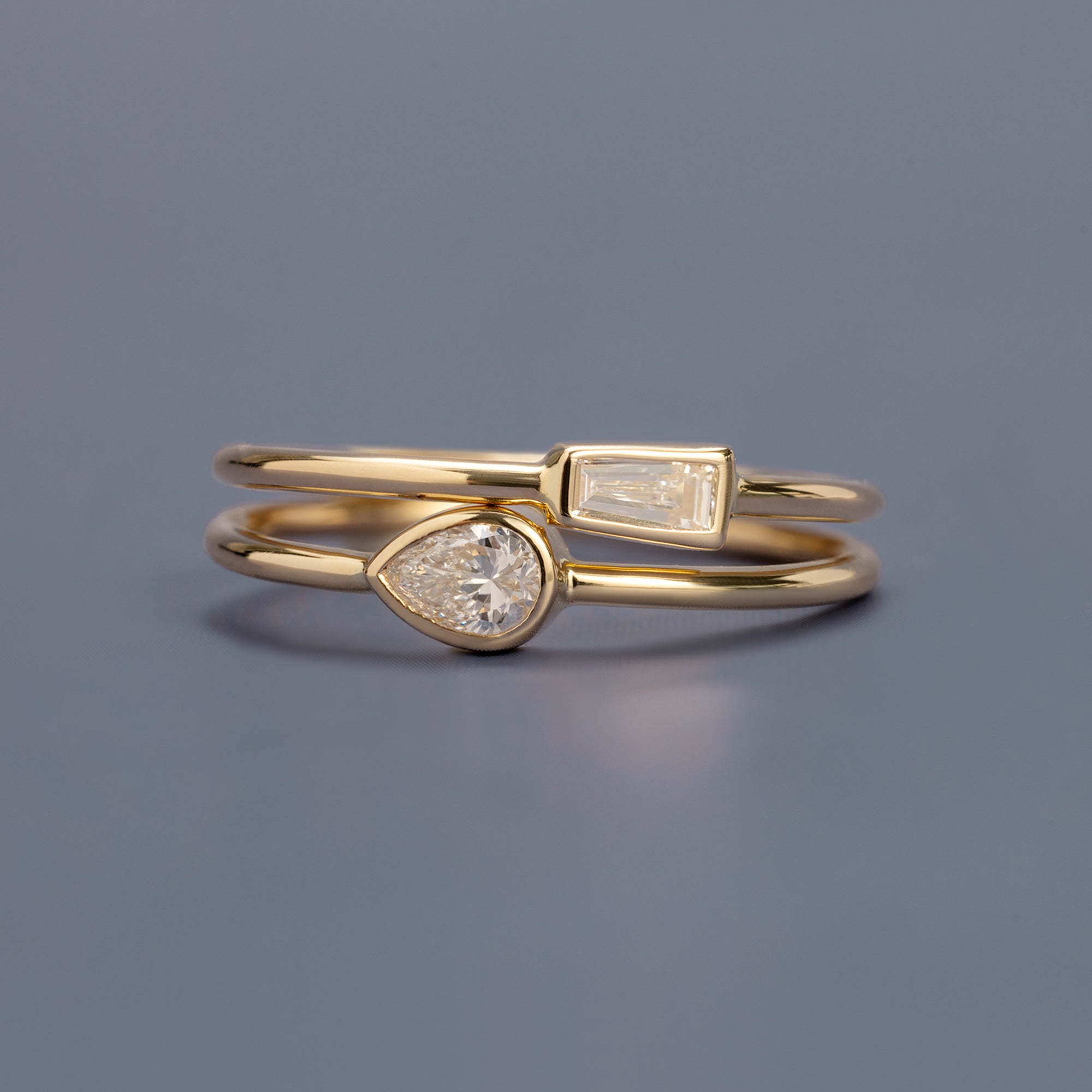 Baguette and Pear Diamond Stacking Rings in 10K Yellow Gold on Blue Background