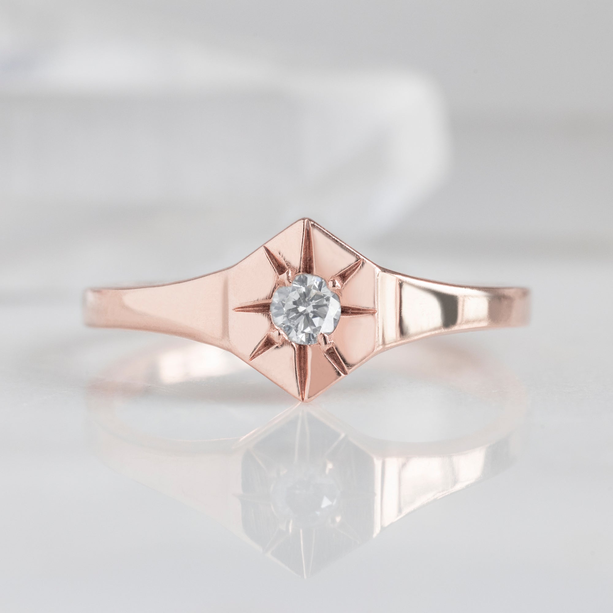 Custom White Diamond Birthstone Signet Ring | 10K Rose Gold, displayed on marble surface.