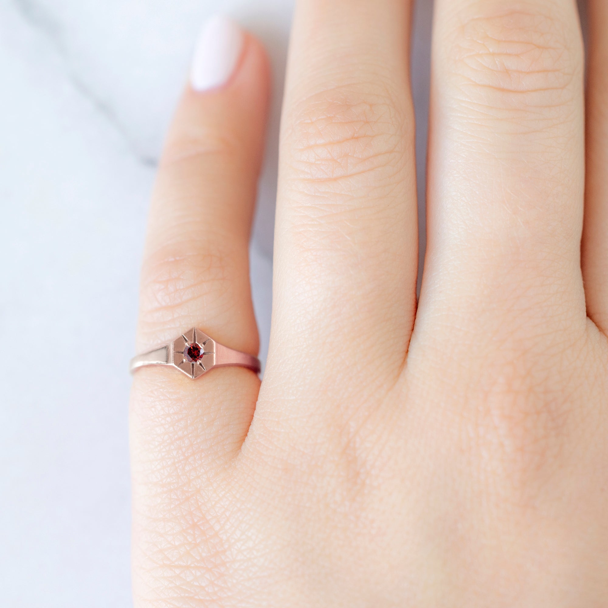 Custom Garnet Birthstone Signet Ring | 10K Rose Gold. Displayed on model's left hand pinky finger.