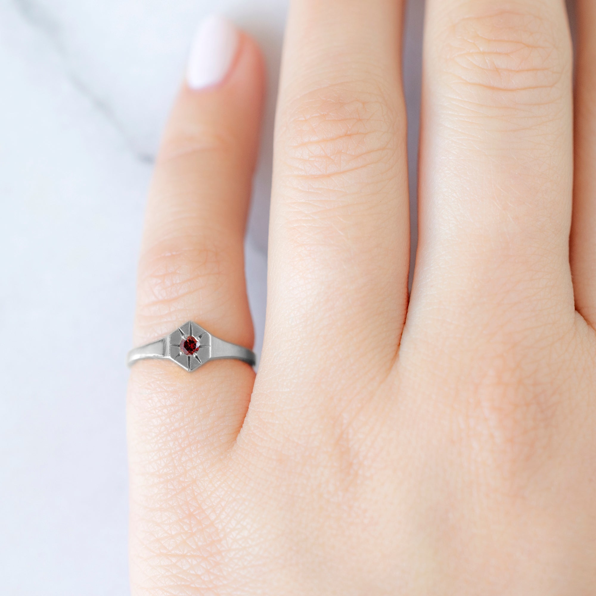 Custom Garnet Birthstone Signet Ring | 10K White Gold. Displayed on model's left hand pinky finger. 