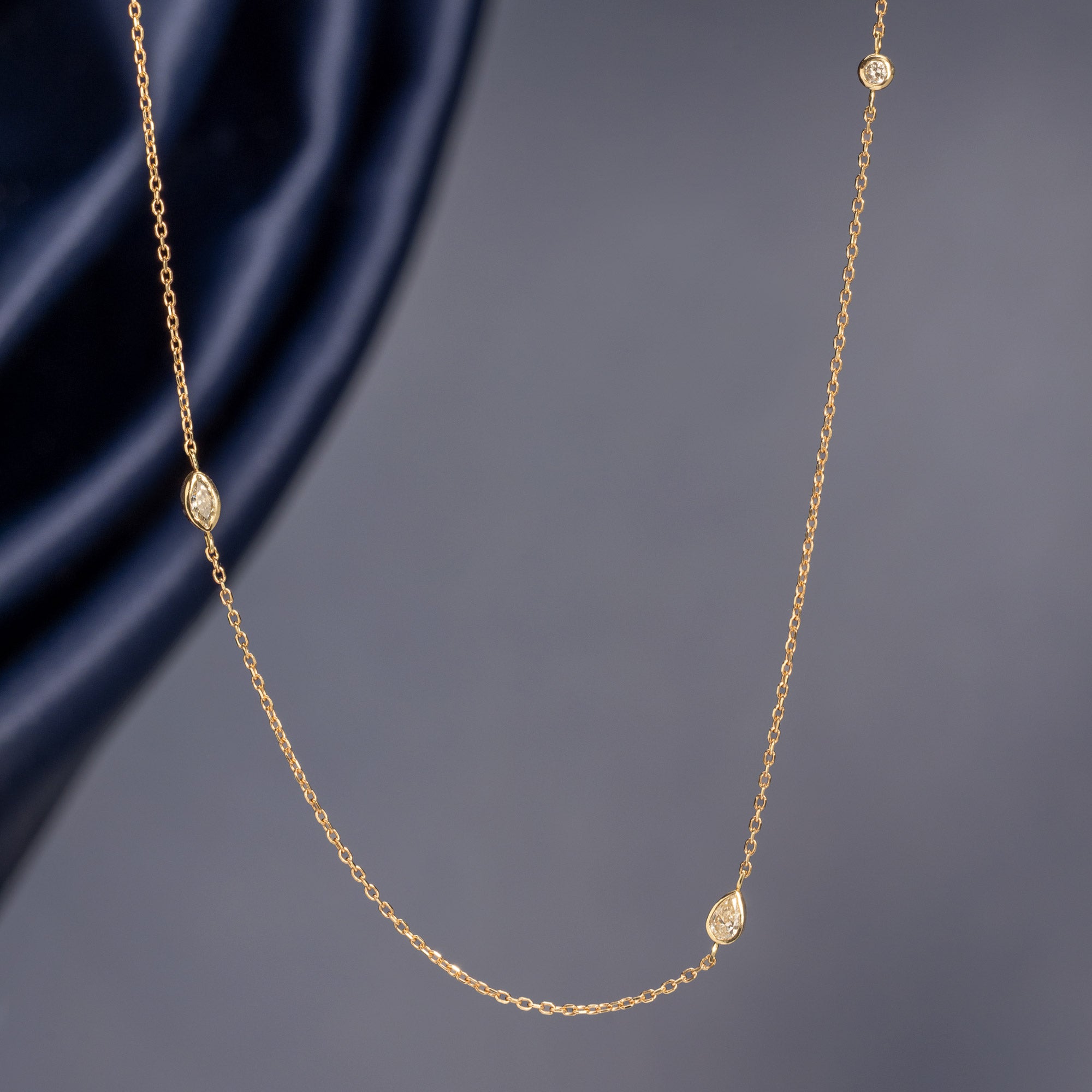 Pear-Cut Diamond Chain Necklace in 10K Yellow Gold hanging in front of muted blue background