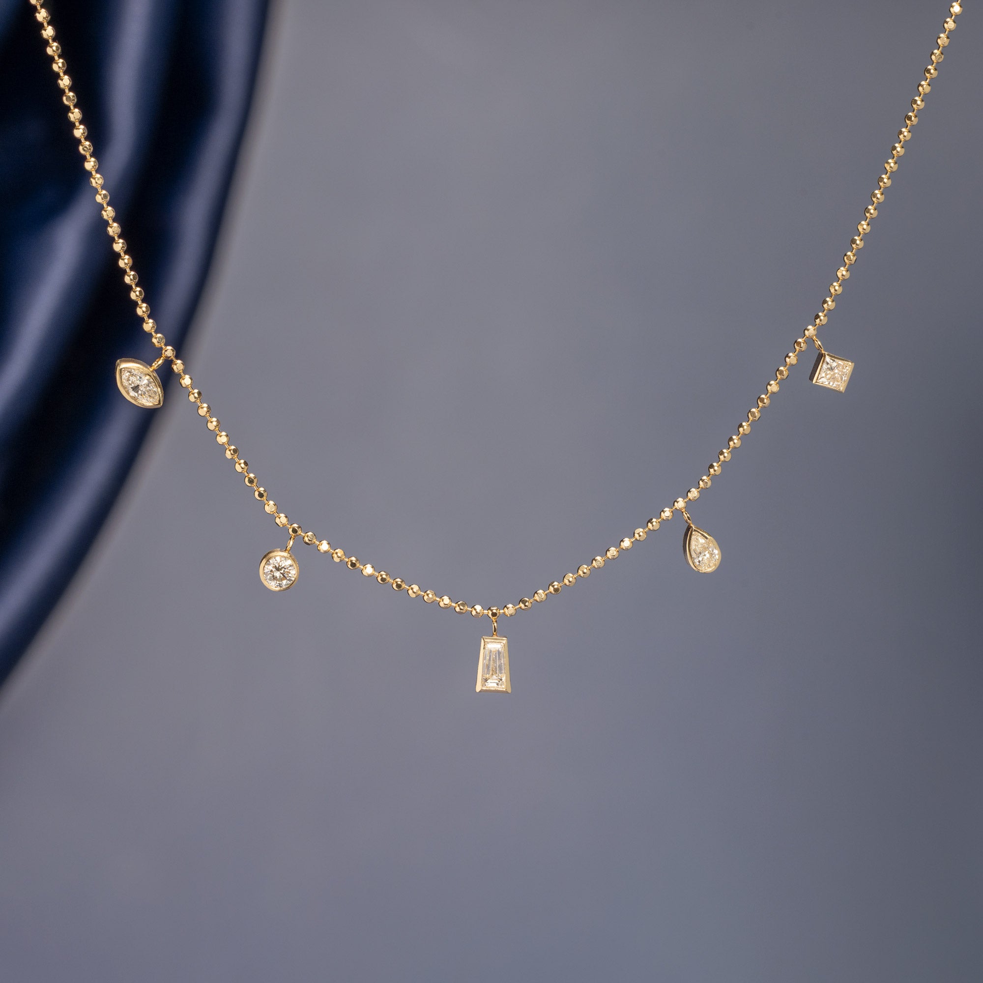 Diamond Pennant Necklace in 10K Yellow Gold on muted blue background