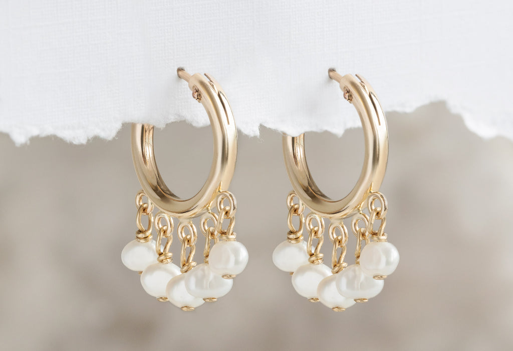 Pearl Party Hoop Earrings hanging on white textured paper