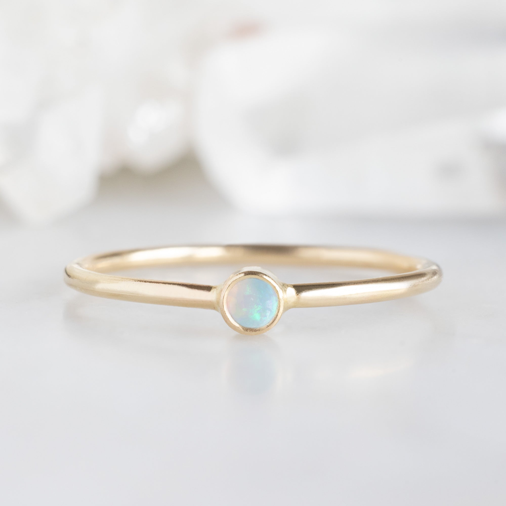 Custom Opal Birthstone Stacking Ring | 10K Yellow Gold displayed on marble surface.