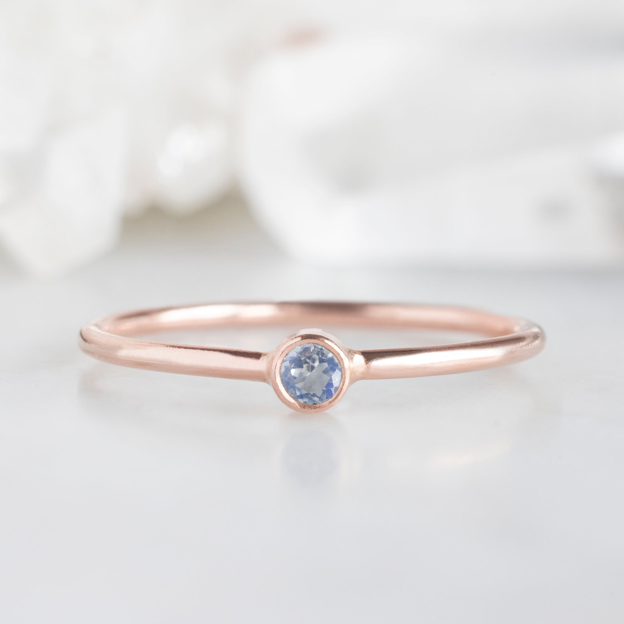 Custom Moonstone Birthstone Stacking Ring | 10K Rose Gold, Displayed on marble surface with white blurred background. 