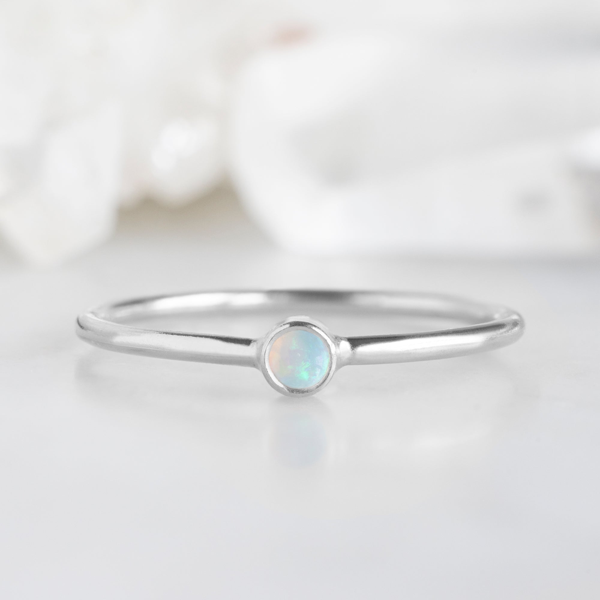 Custom Opal Birthstone Stacking Ring | 10K White Gold displayed on marble surface. 