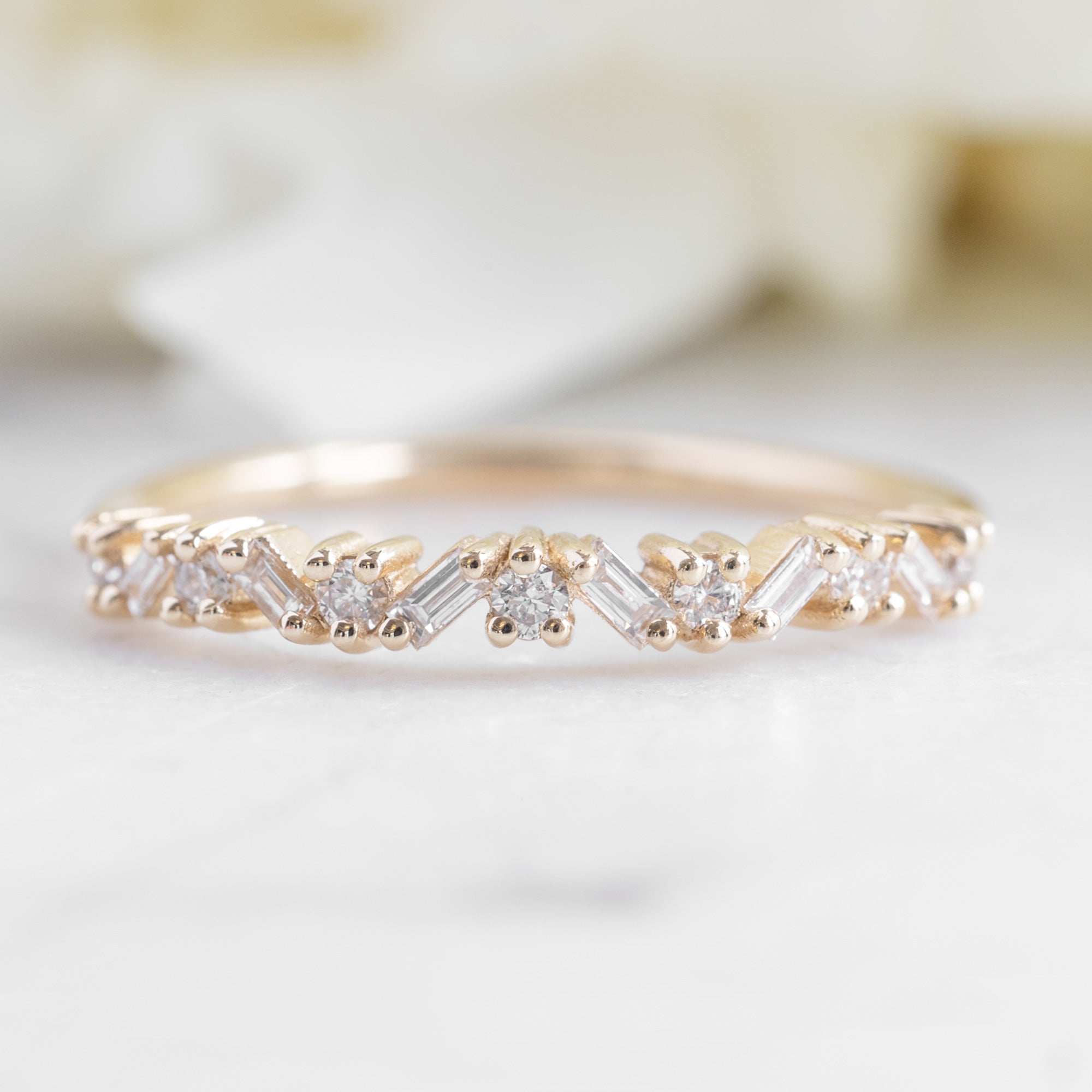 The Baguette Confetti Stacking Ring In Yellow Gold on marble surface 