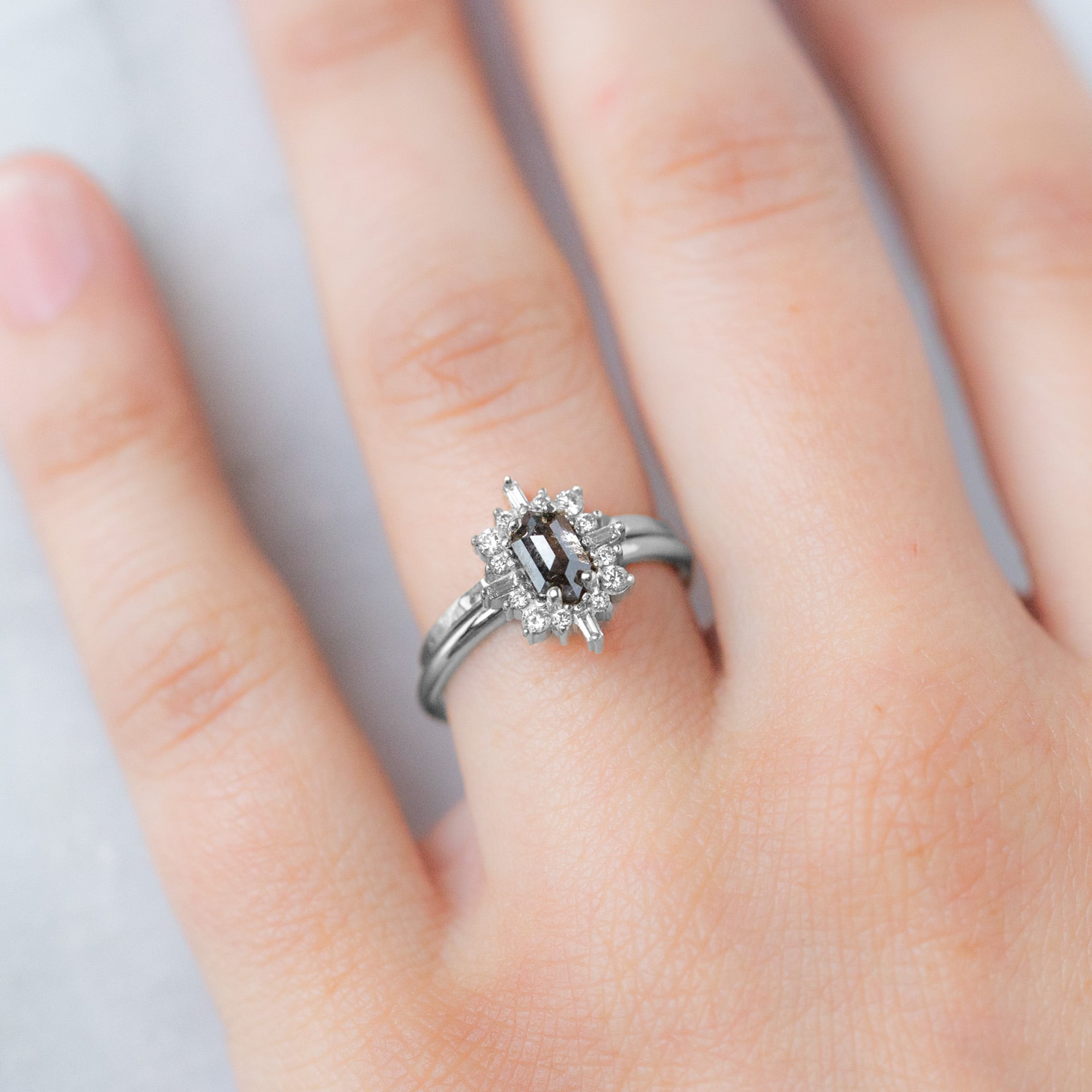 The Gold Stacking Wedding Ring | Hammered Texture in 14K White Gold displayed on model's left hand ring finger paired with a black diamond engagement ring. 